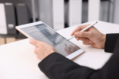 Photo of Electronic signature. Man using stylus and tablet at white table, closeup