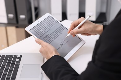 Photo of Electronic signature. Man using stylus and tablet at white table, closeup