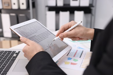 Photo of Electronic signature. Man using stylus and tablet at table indoors, closeup