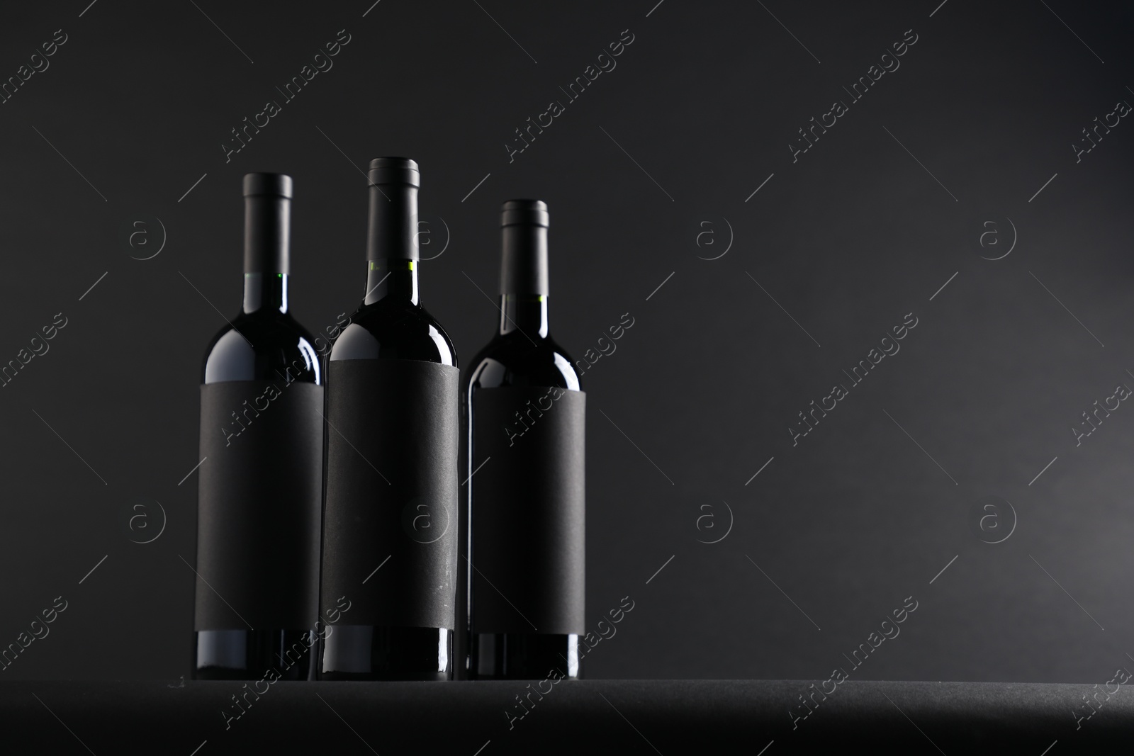 Bottles of wine on black background, space for text Photo of Bottles of wine on black background, space for text