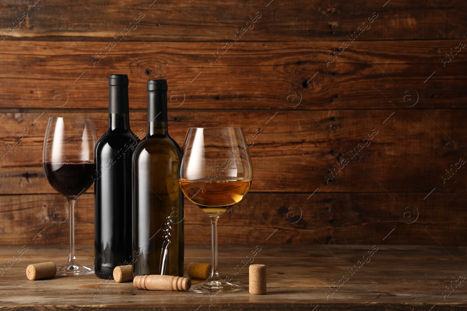 Tasty wine in glasses, bottles, corks and corkscrew on wooden table, space for text Photo of Tasty wine in glasses, bottles, corks and corkscrew on wooden table, space for text
