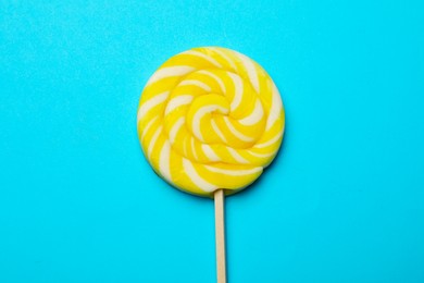 Tasty striped lollipop on light blue background, top view