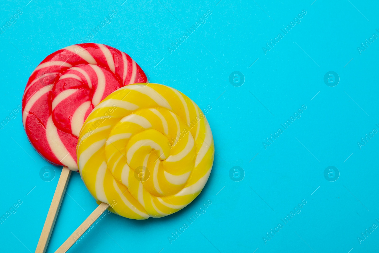 Photo of Tasty lollipops on light blue background, flat lay. Space for text