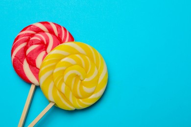 Tasty lollipops on light blue background, flat lay. Space for text