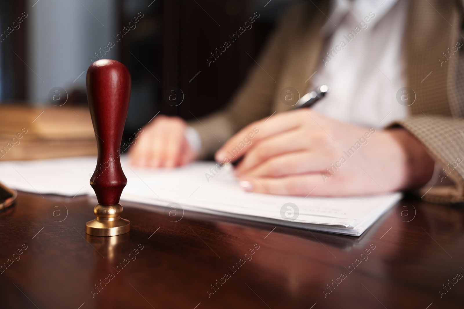 Photo of Notary working at table in office, focus on stamp