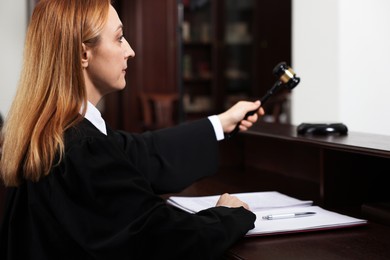 Photo of Judge striking gavel at wooden table in courtroom