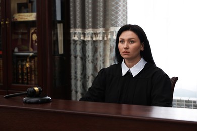 Photo of Judge in court dress at wooden table indoors