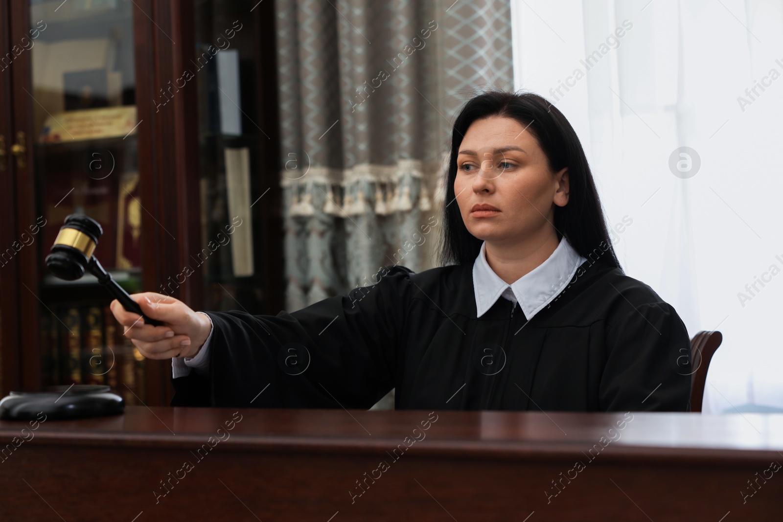 Photo of Judge striking gavel at wooden table in courtroom