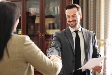 Photo of Smiling notary shaking hands with client in office