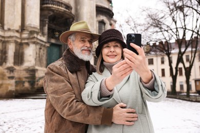 Happy senior couple taking selfie on winter day