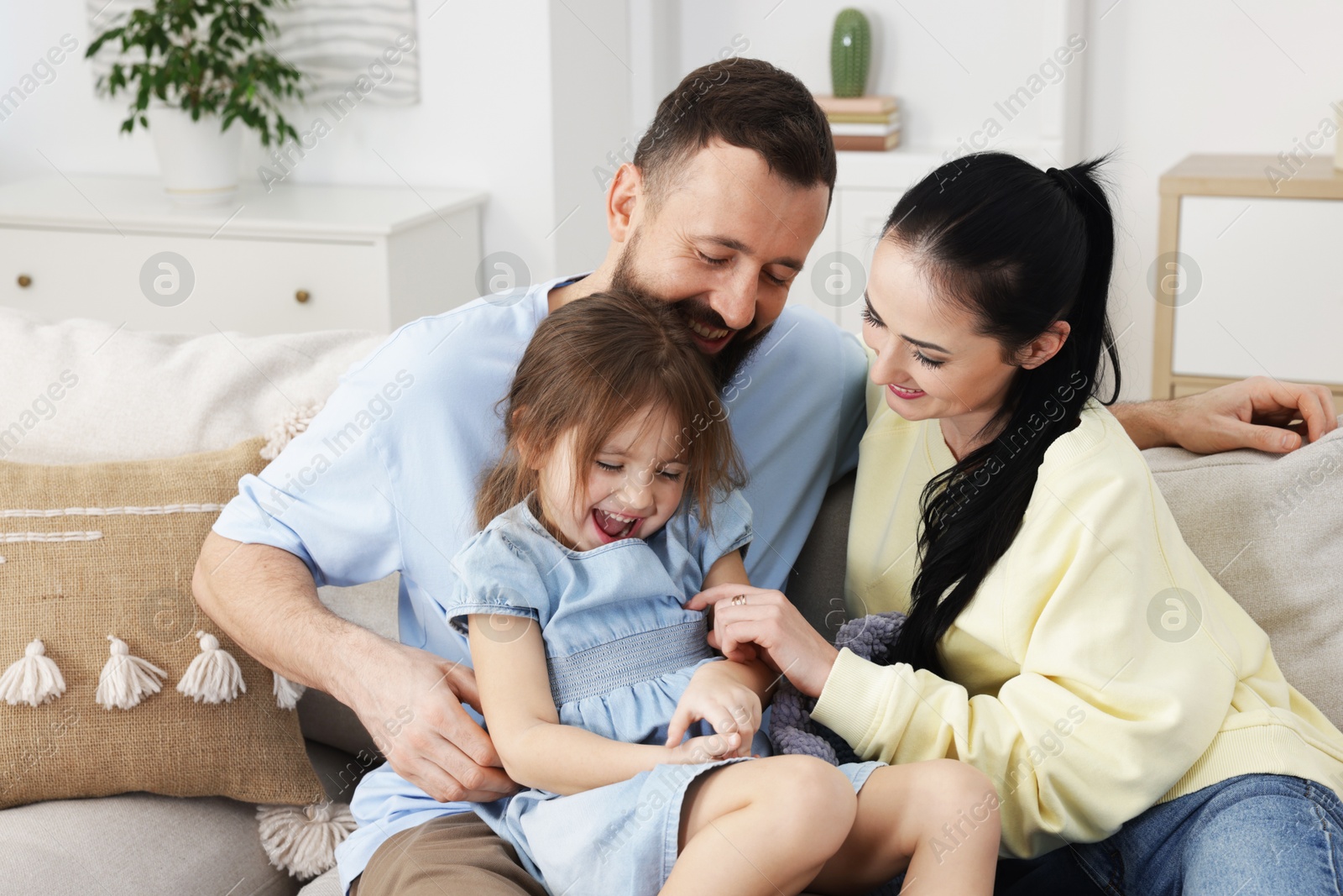 Photo of Cute little girl and her parents having fun at home