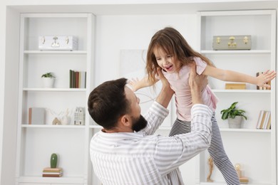 Photo of Cute little girl and her father having fun at home