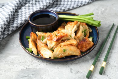 Photo of Tasty fried gyoza (dumplings) and soy sauce on light grey table, closeup