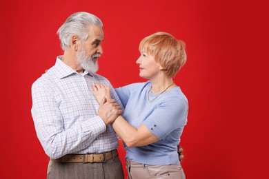 Photo of Lovely senior couple looking at each other on red background