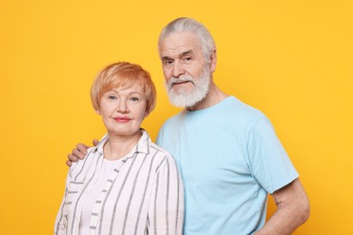 Portrait of lovely senior couple on orange background