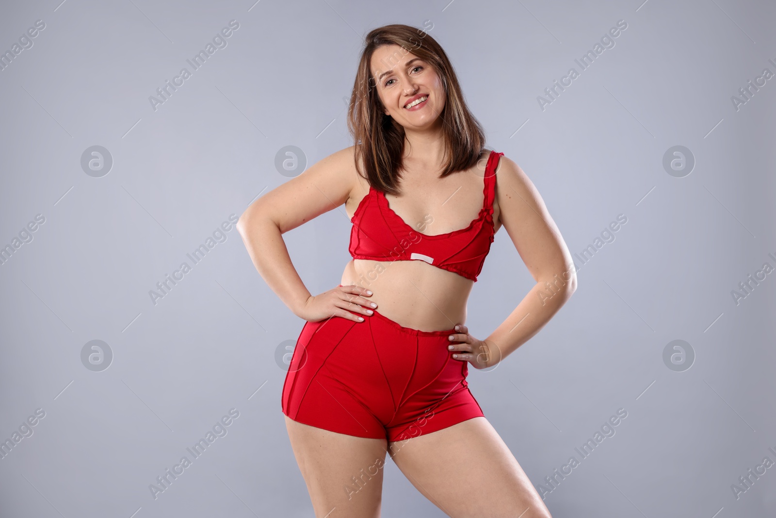 Photo of Woman in red underwear on light grey background. Cellulite problem