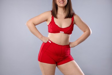 Woman in red underwear on light grey background, closeup. Cellulite problem