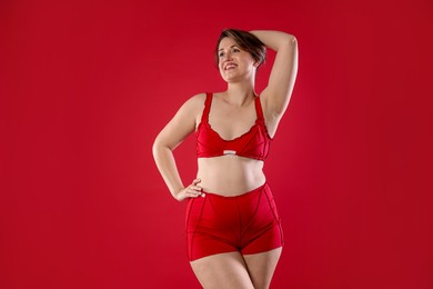 Woman in underwear on red background. Cellulite problem