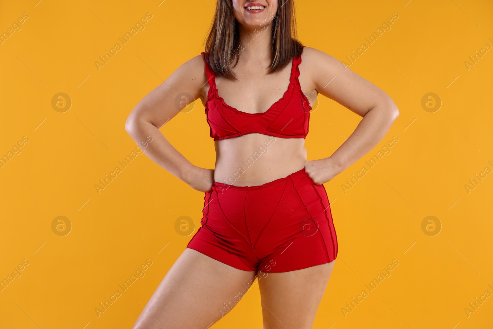 Photo of Woman in red underwear on orange background, closeup. Cellulite problem