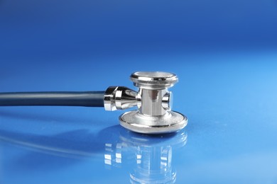 Photo of Stethoscope on blue background, closeup. Medical tool