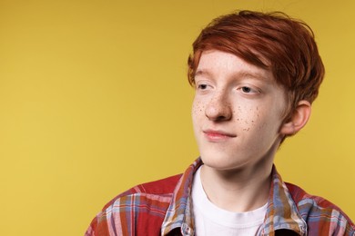 Teenage boy with freckles on yellow background. Space for text