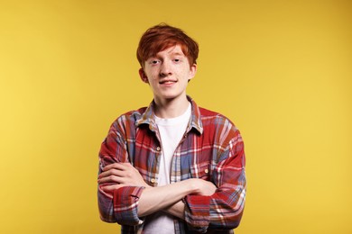 Portrait of smiling teenage boy with freckles on yellow background