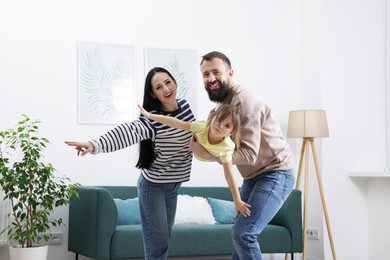 Photo of Cute little girl and her parents having fun at home