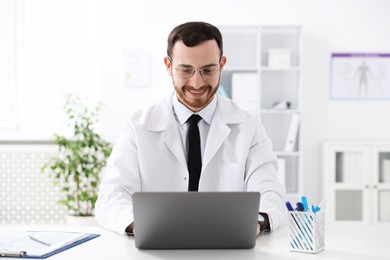 Professional doctor working on laptop at desk in hospital