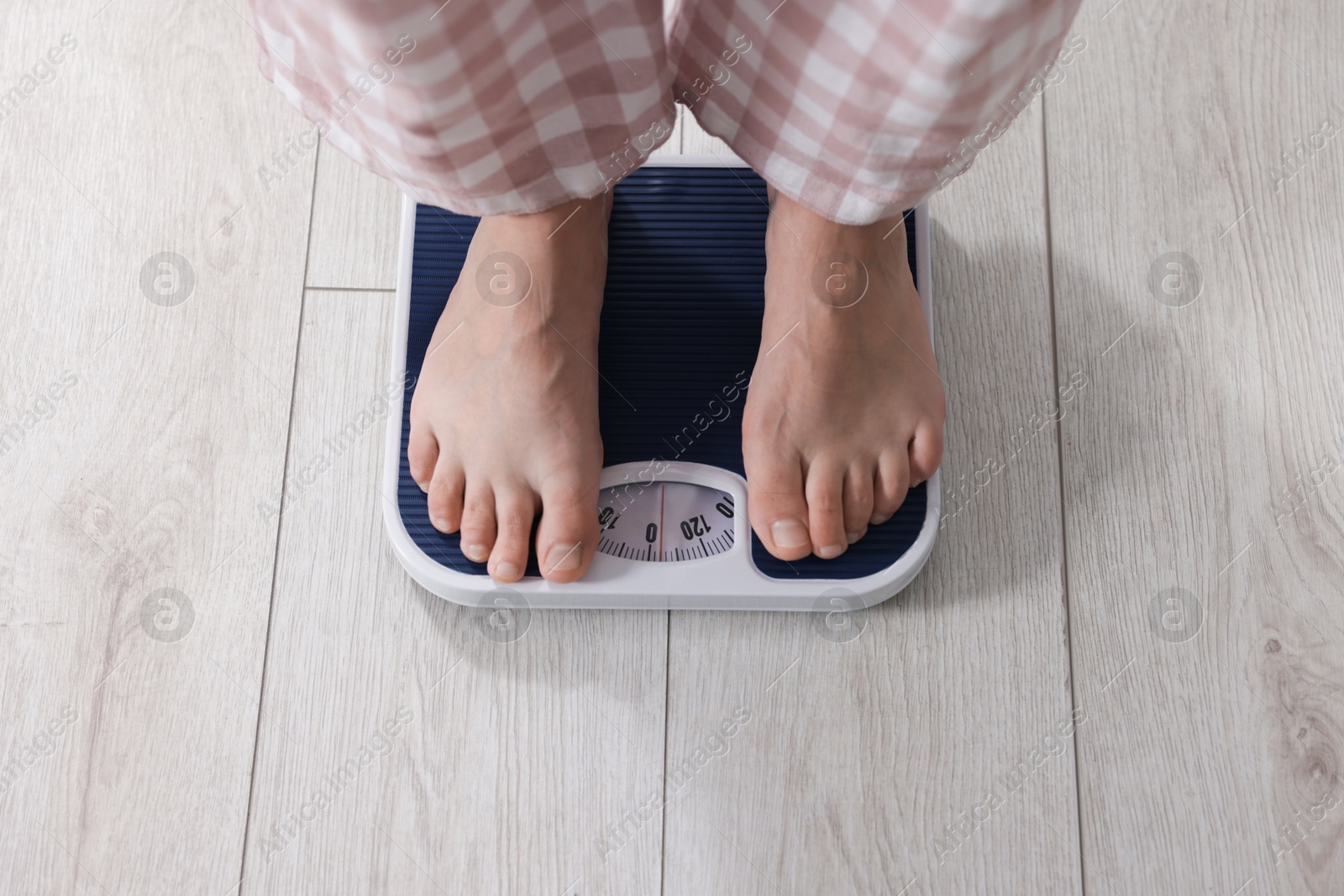 Photo of Woman on scales indoors, above view. Weight loss