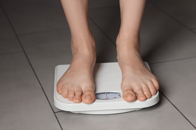 Photo of Woman on scales indoors, closeup. Bulimia problem