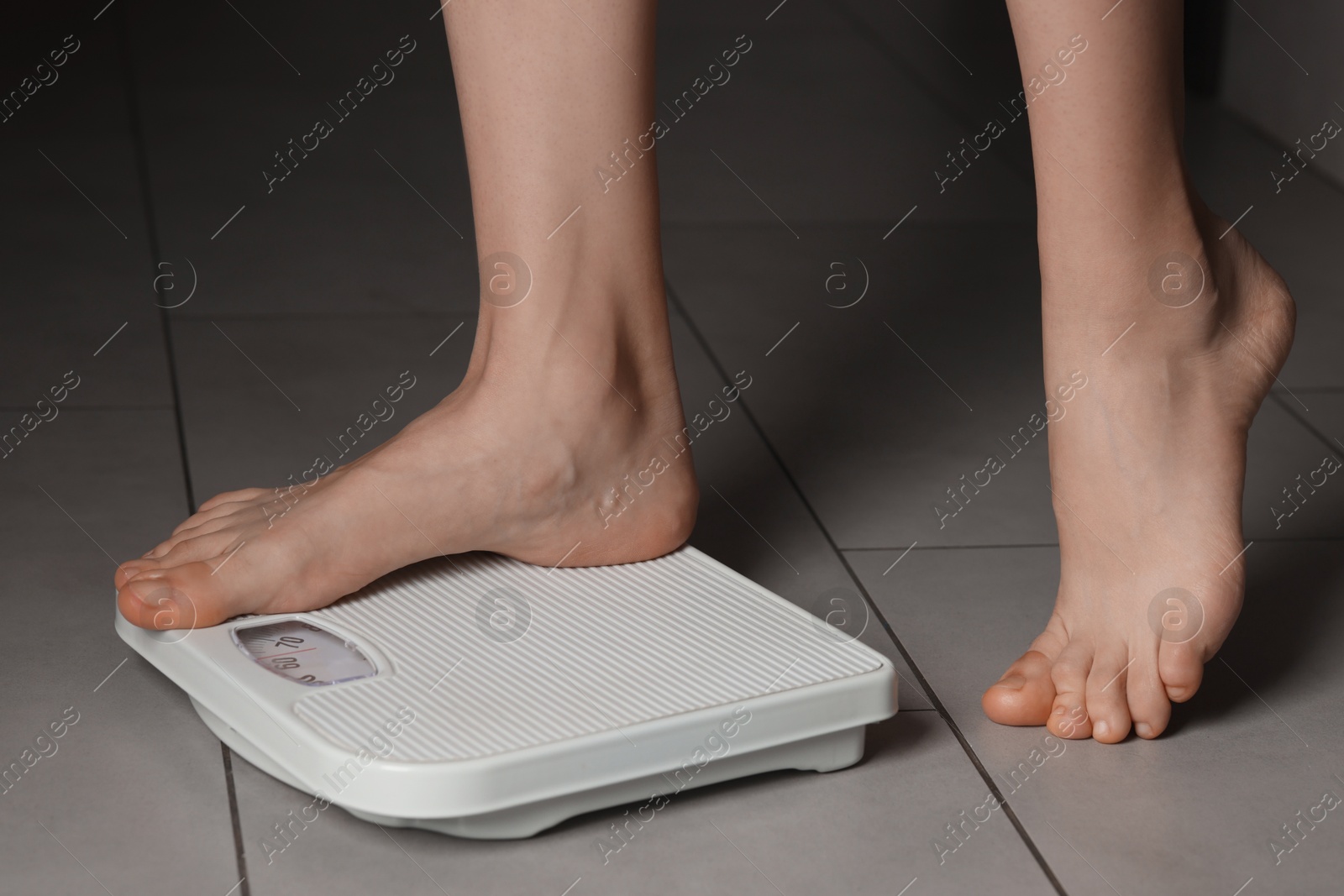 Photo of Woman on scales indoors, closeup. Bulimia problem