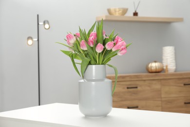 Photo of Bouquet of beautiful tulips in vase on white table indoors