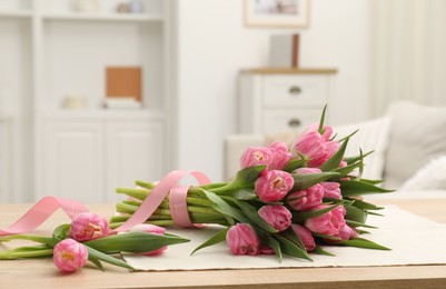 Photo of Bouquet of beautiful tulips on wooden table indoors