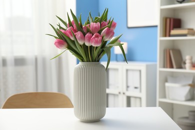 Photo of Bouquet of beautiful tulips in vase on white table indoors