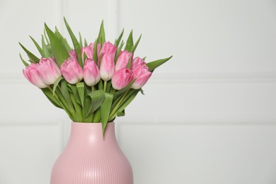 Photo of Bouquet of beautiful tulips in vase near white wall indoors, space for text