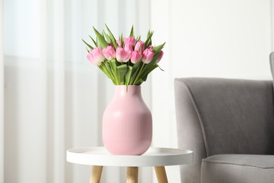 Photo of Bouquet of beautiful tulips in vase on white table indoors