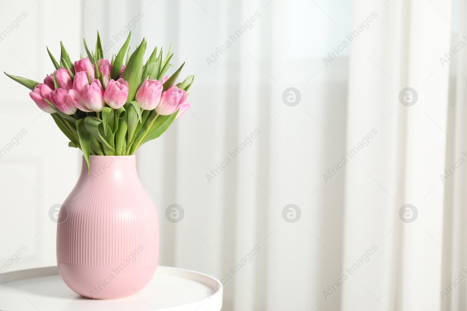 Photo of Bouquet of beautiful tulips in vase on white table indoors, space for text