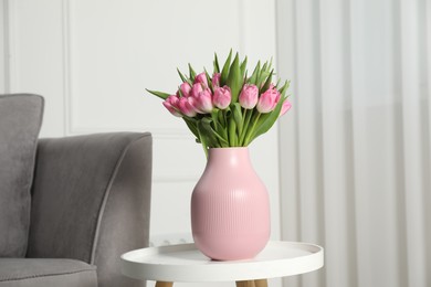 Photo of Bouquet of beautiful tulips in vase on white table indoors