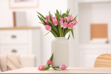 Photo of Bouquet of beautiful tulips in vase on wooden table indoors