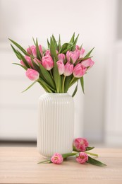 Photo of Bouquet of beautiful tulips in vase on wooden table indoors