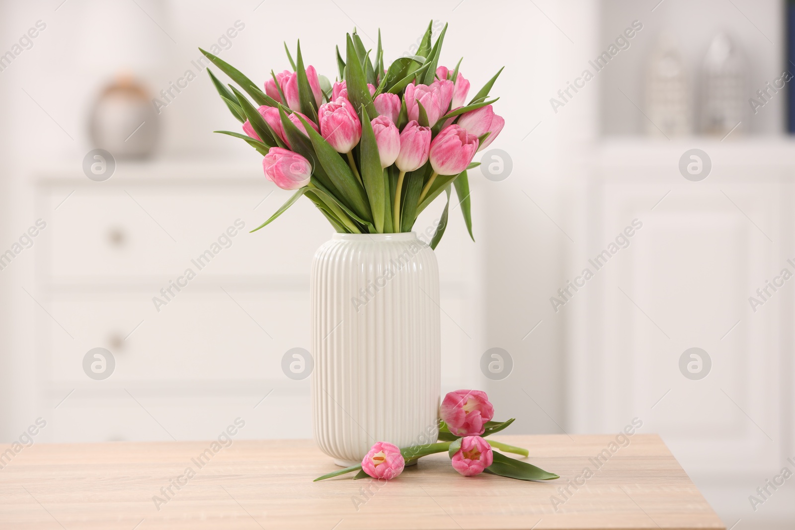 Photo of Bouquet of beautiful tulips in vase on wooden table indoors