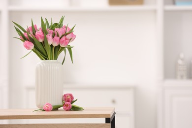 Photo of Bouquet of beautiful tulips in vase on wooden table indoors, space for text