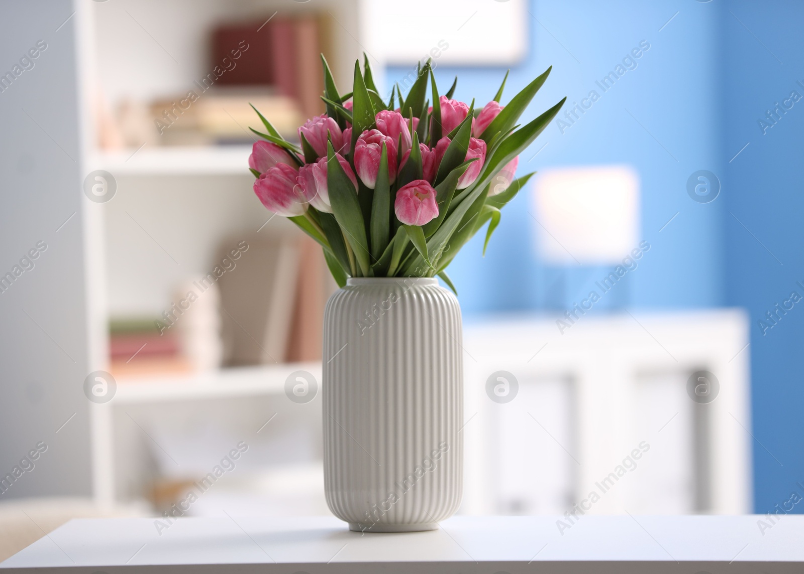 Photo of Bouquet of beautiful tulips in vase on white table indoors