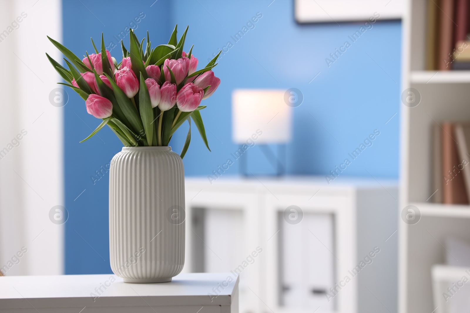 Photo of Bouquet of beautiful tulips in vase on white table indoors, space for text