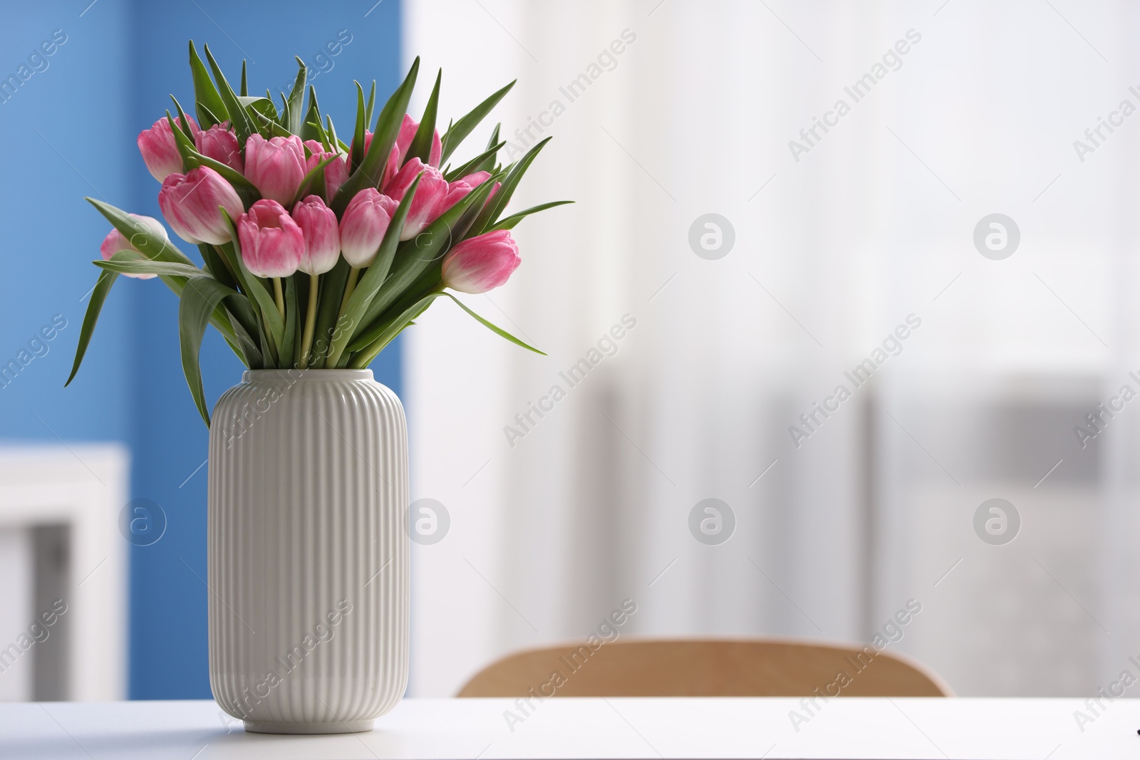 Photo of Bouquet of beautiful tulips in vase on white table indoors, space for text