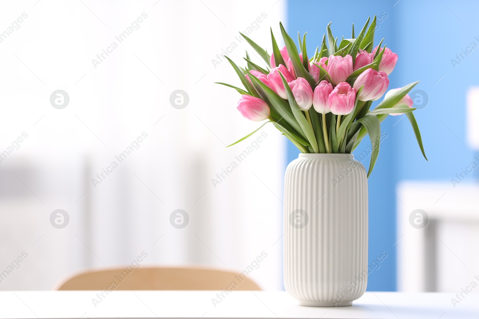 Photo of Bouquet of beautiful tulips in vase on white table indoors, space for text