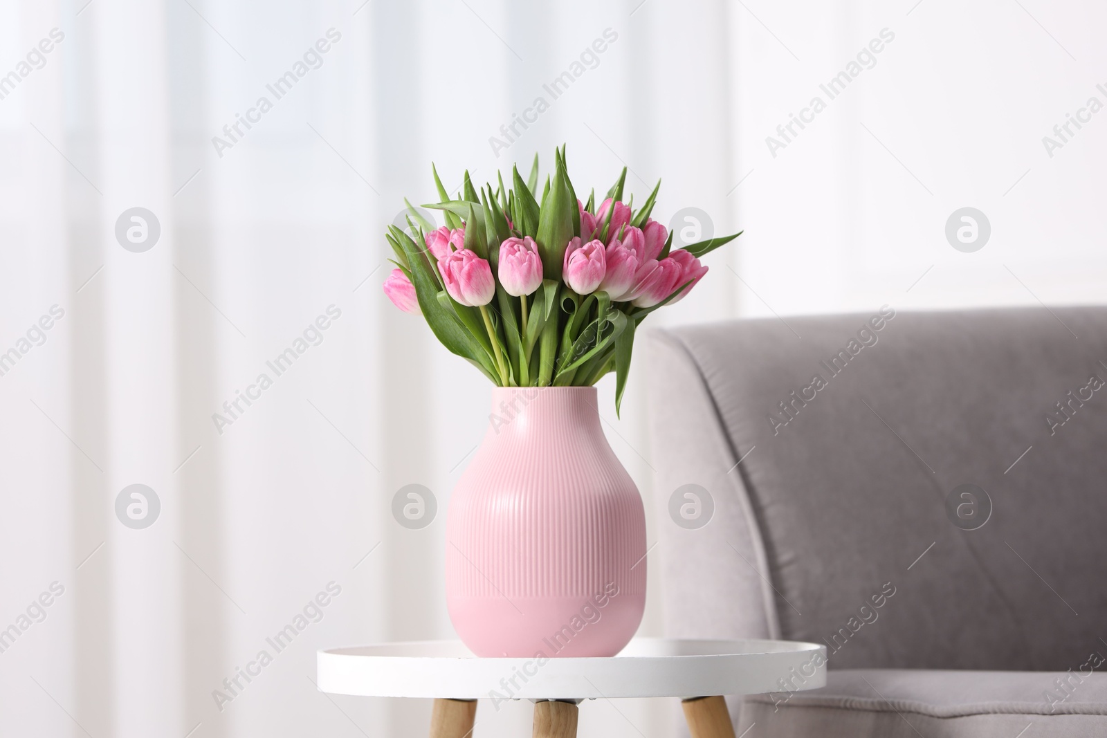 Photo of Bouquet of beautiful tulips in vase on table indoors