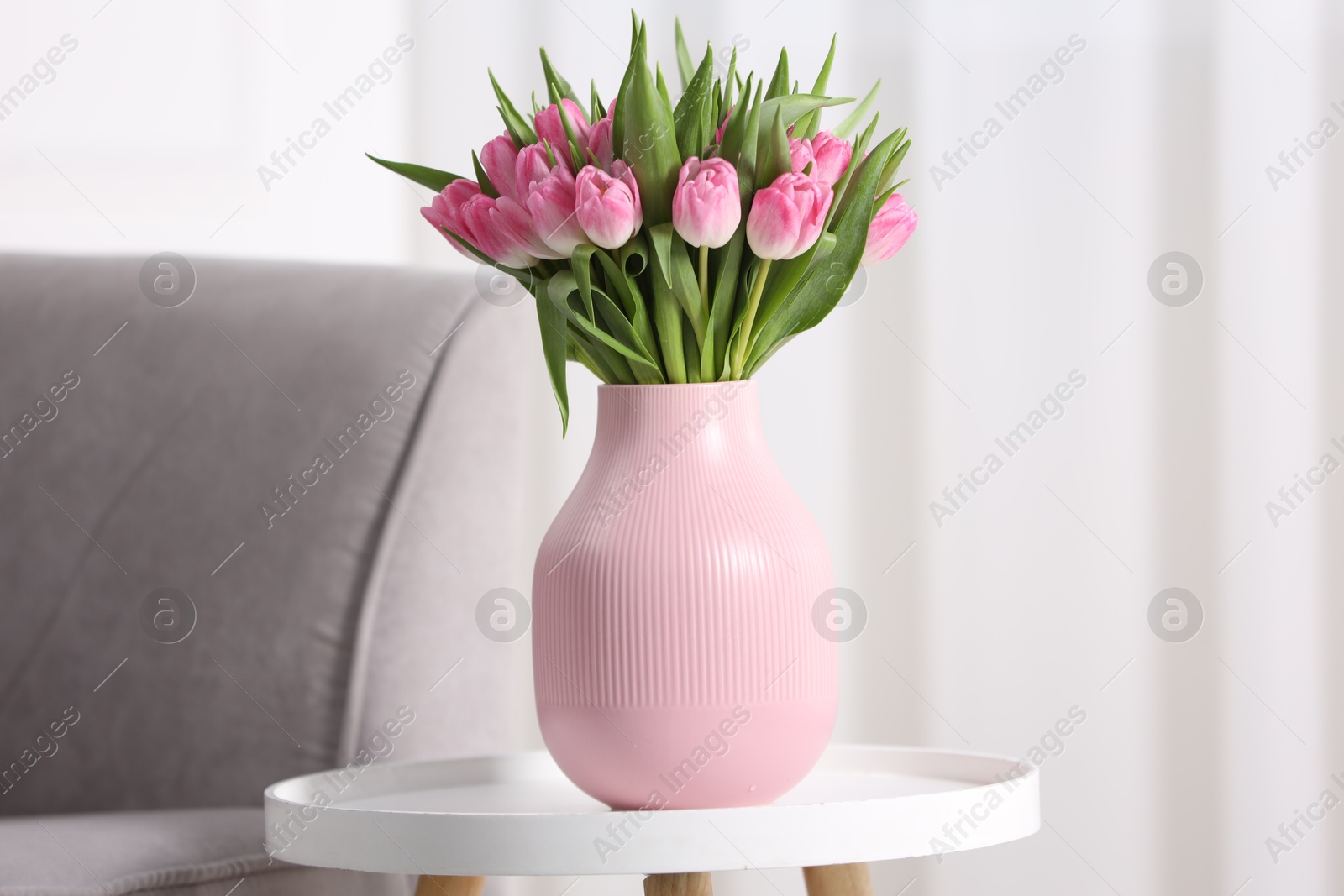 Photo of Bouquet of beautiful tulips in vase on table indoors