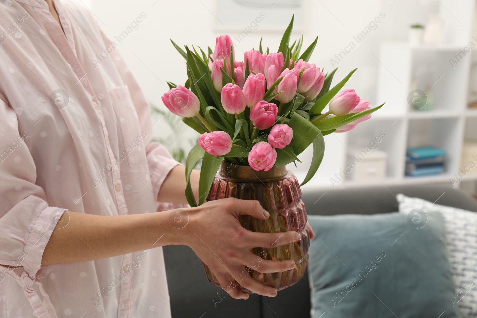 Photo of Woman holding vase with bouquet of beautiful tulips indoors, closeup. Space for text