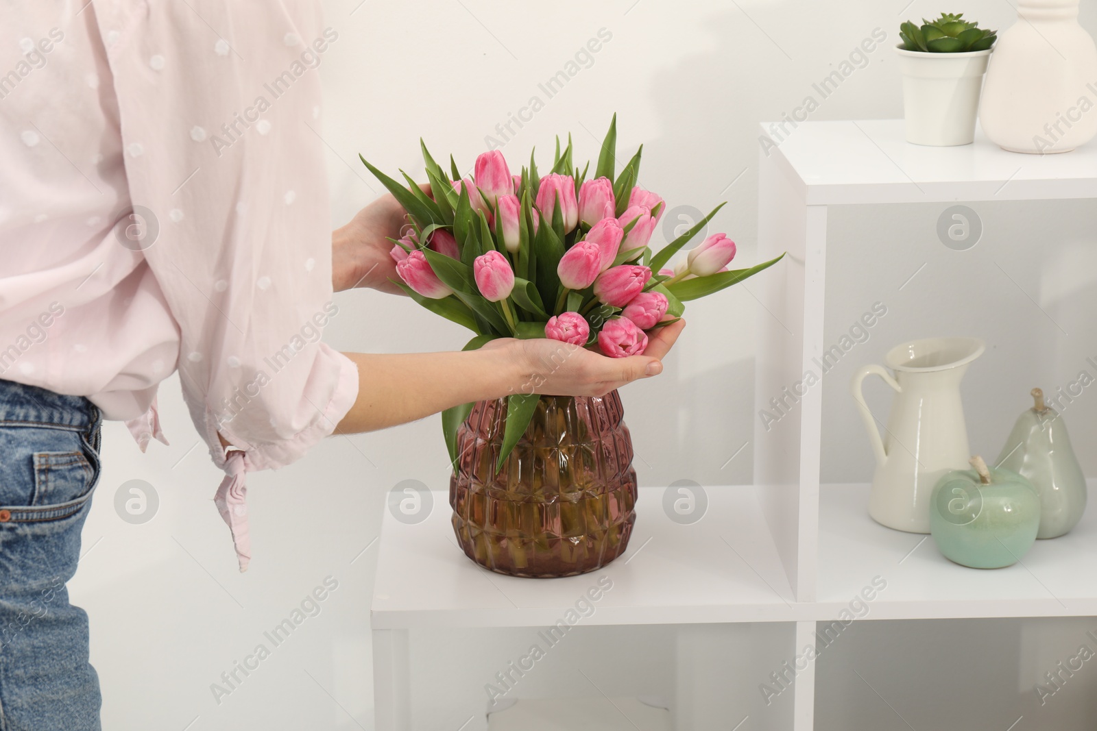 Photo of Woman with bouquet of beautiful tulips near shelving unit indoors, closeup